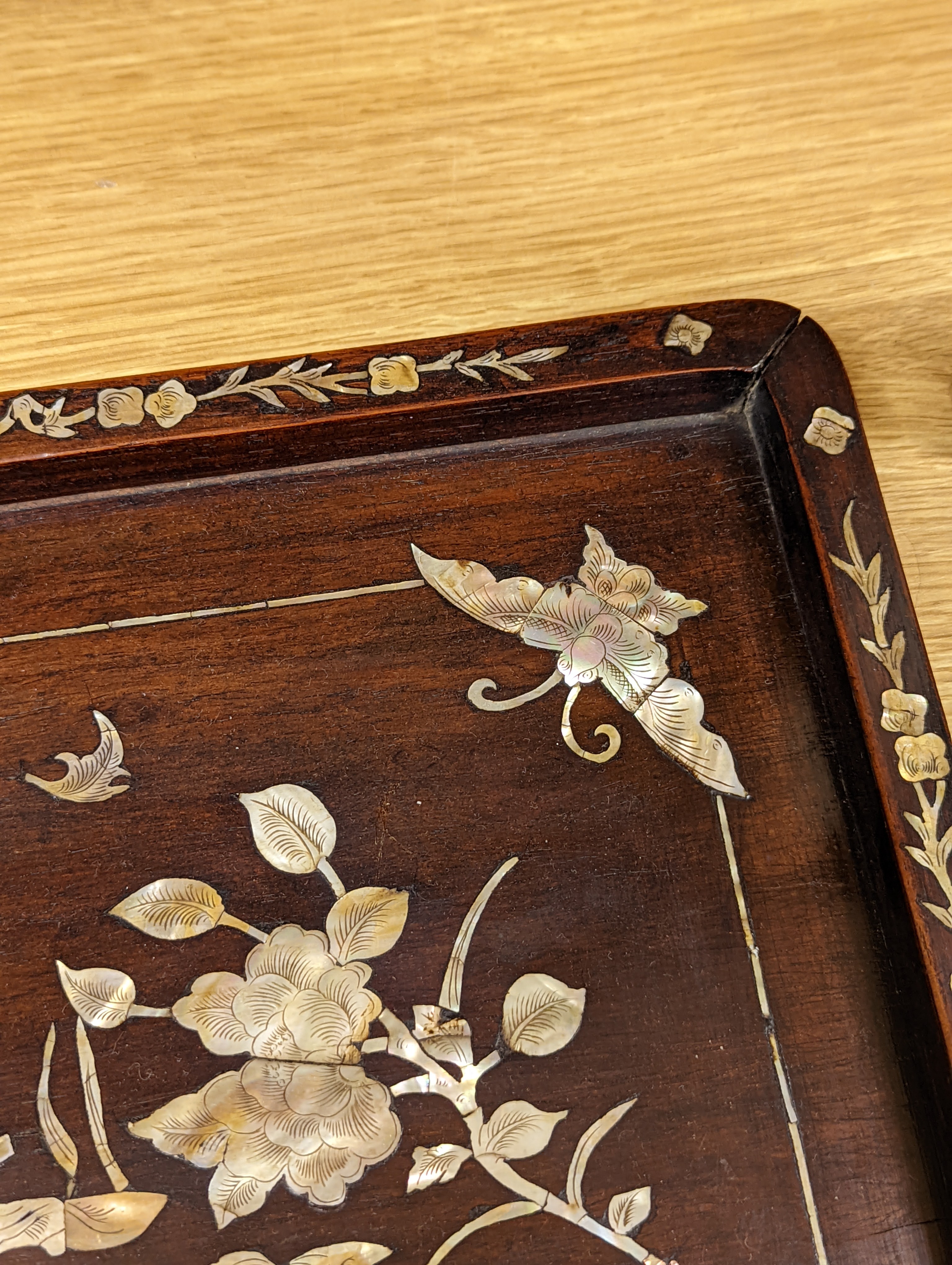 Two Chinese mother of pearl inlaid hongmu trays, the rectangular example with birds and insects amid flowers and the smaller oval example with a pavilion in a landscape within floral sprays 55x34cm